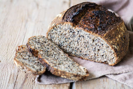 Homemade rye sourdough bread with black sesame on a napkin on a wooden background.の写真素材