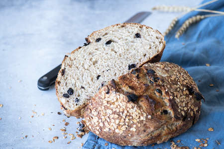 Sourdough bread with raisins and oats on a blue napkin on a gray background. Fermented food concept.の写真素材