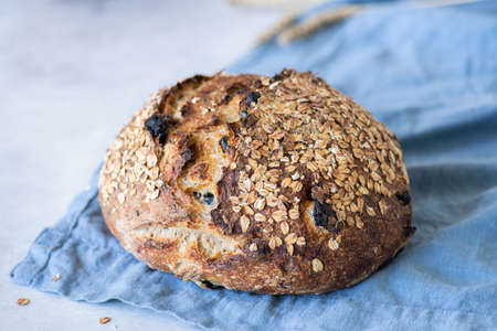 Sourdough bread with raisins and oats on a blue napkin on a gray background. Fermented food concept.