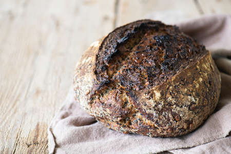 Homemade rye sourdough bread with black sesame on a napkin on a wooden background.の写真素材