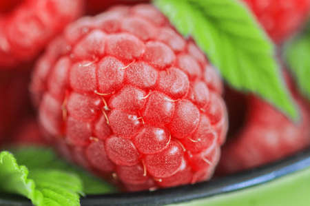 Fresh ripe red raspberries in a green jar. close up.