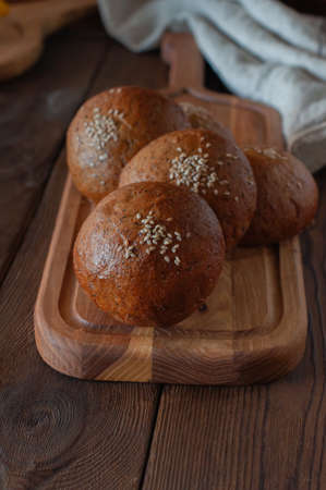 Freshly baked whole wheat buns on a wooden board. close up.