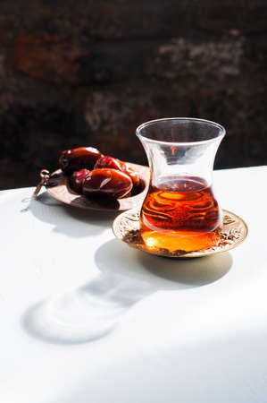 Red tea in glass, dates in the plate and hard light with harsh shadows, Close up.の写真素材