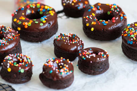 Chocolate baked donuts with chocolate frosting and sprinkles.の写真素材
