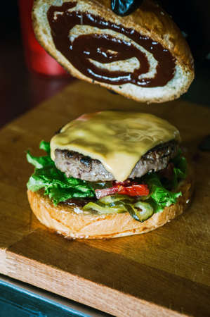 Rich cheeseburger in making, fluffy buns, beef burger meat, lettuce, bbq sauce and cheese.の写真素材