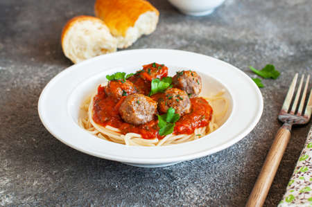 Spaghetti with meatballs and tomato sauce in a white plate on a gray background.の写真素材