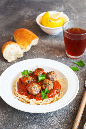 Spaghetti with meatballs and tomato sauce in a white plate on a gray background. close up.の写真素材