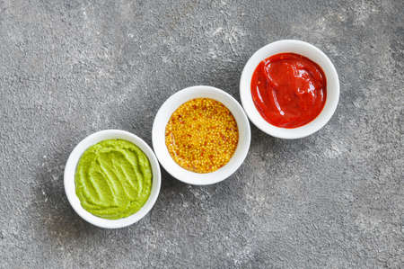 Assorted sauces, french mustard, ketchup and guacamole on a gray background. top view.の写真素材