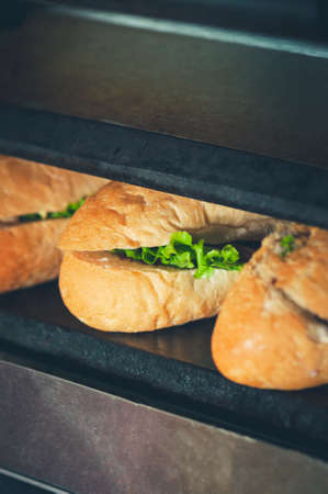 Sandwiches in the making. Fresh buns with filling on the plancha grill.