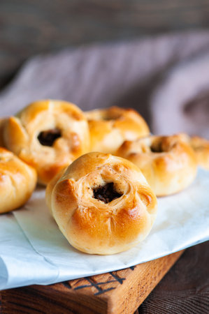 Middle Asian authentic baked meat hand pies - belyash or samsa served on baking paper on wooden background.の写真素材