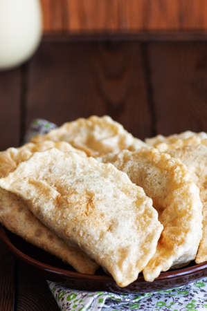 Freshly fried empanadas or chebureki with meat served on a plate. wooden background. close up.の写真素材