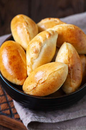 Potato stuffed hand pies in a black bowl on a wooden board. overhead view.の写真素材