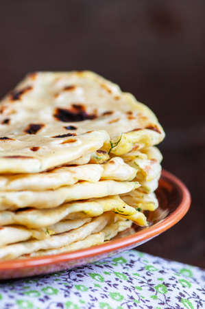 Stack of Khychin - traditional flatbreads stuffed with mashed potatoes and greens served on a plate.