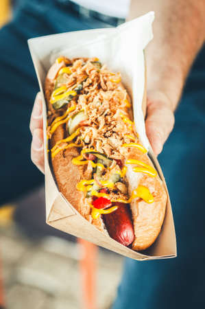 Freshly prepared hotdog with lush salsa cauce in a paper box. Food delivery or take away food concept.の写真素材