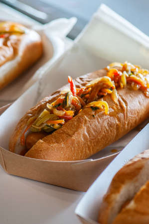 Freshly prepared hotdogs with spicy salsa in a paper box. Food delivery or take away food concept.の写真素材