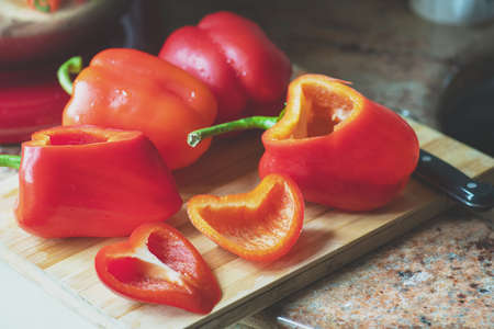 Cutted red bell peppers ready for preparing on a wooden board.の写真素材