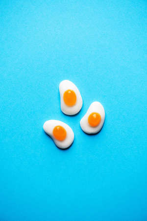Three egg shaped sweet marmalade on a blue background. top view. copyspace.の写真素材
