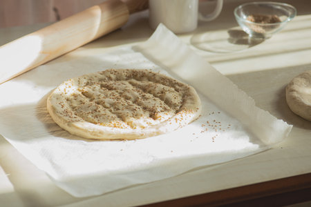 Round dough on a table, preparing ramadan pide with sesame seeds.