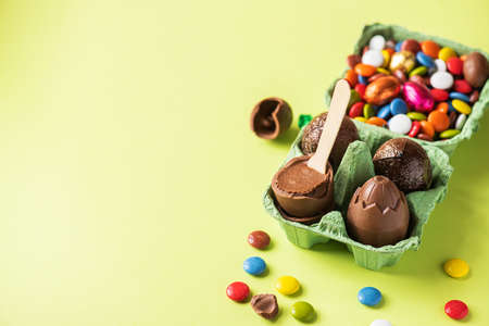 Chocolate Easter eggs with cream filling and colorful candies on a green background. Topview.の写真素材
