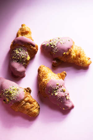 Mini-croissants with ruby chocolate and pistachios on a pink background. Top view.の写真素材