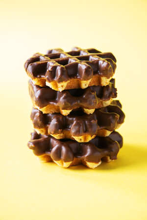 Stack of chocolate waffles. Close up and yellow background, copy space.の写真素材