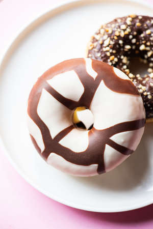 Two donuts with chocolate glaze and peanuts on a pink background. close up.の写真素材