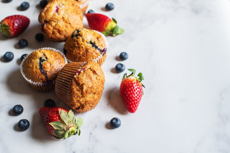 Blueberry and strawberry muffins with berries on a marble background. Close up and copy space.の写真素材