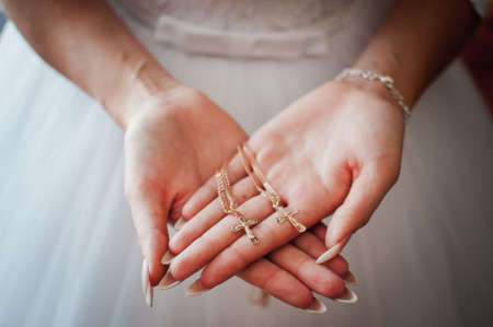 Bride holding gold christian crests in the handsの写真素材