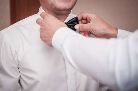 Man helps groom to wear tiebow