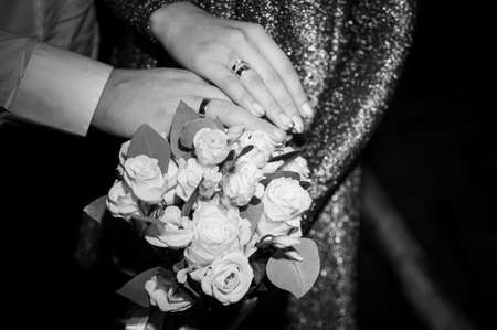 Groom and bride holding wedding bouquet in the hand black and white