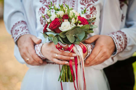 Groom and bride holding colorfull wedding bouquet in the hand