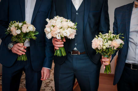 Mans in suits holding bouquet of flowers in the handsの写真素材