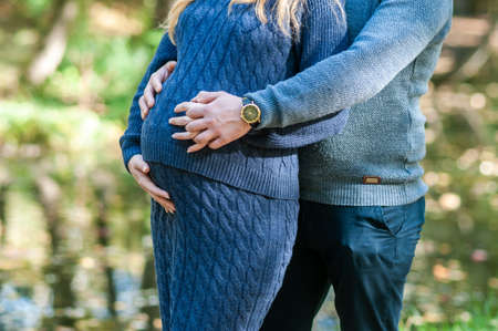 Pregnant woman and man hold hands in the shape of a heartの写真素材