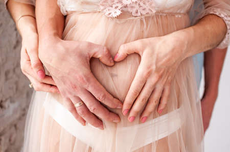 man and woman holding hands on pregnant bellyの写真素材