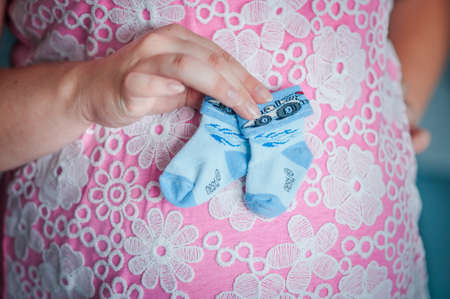 pregnant woman holding small socks on the bellyの写真素材