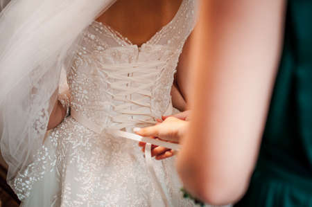 Bridesmaids assist bride to wear wedding dressの写真素材