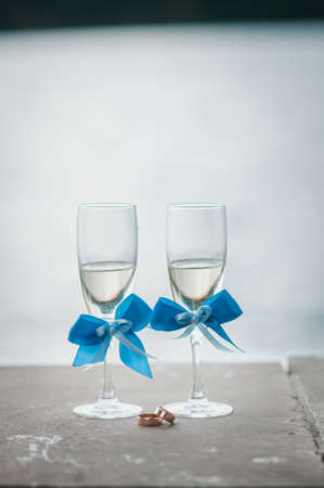 Glasses of champagne and gold wedding rings lies on the tileの写真素材