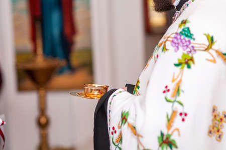 Priest holding gold cup with wine in the hands