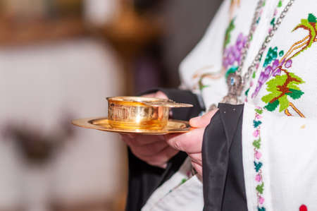 Priest holding gold cup with wine in the handsの写真素材