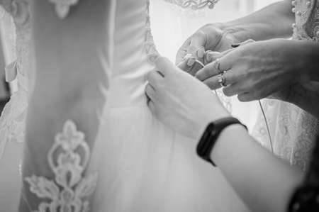bridesmaids lace up the bride's dress black and whiteの写真素材