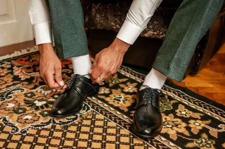 White man puts black shoes on the white backgroundの写真素材