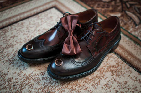Brown man shoes tiebow and pair of gold wedding rings