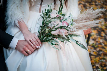 Groom and bride. Groom and bride. Bouquet of roses and white feather in the handの写真素材