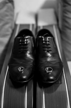 Black mans shoes with gold wedding rings on it black and whiteの写真素材