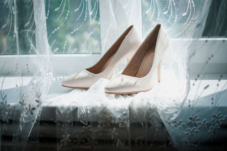 Pair of wedding high heel shoes on the windowsillの写真素材