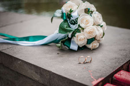 White wedding bouquey of roses and pair of wedding ringsの写真素材