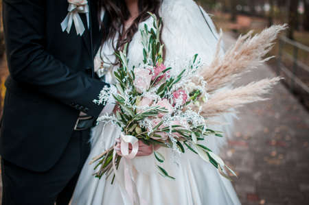 Groom and bride. Groom and bride. Bouquet of roses and white feather in the handの写真素材