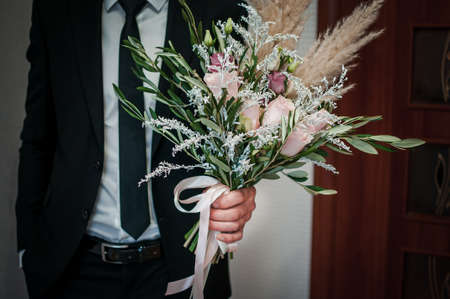 Bouquet of roses and white feather in the grooms handの写真素材