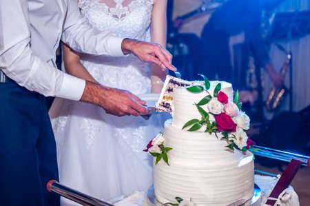 Bride and groom cuting white wedding cakeの写真素材