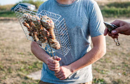 Man holding grid with meat for the barbequeの写真素材